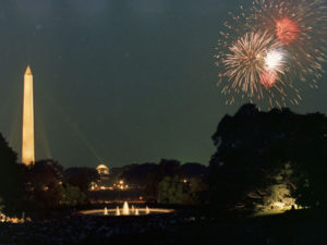 A large audience of White House Staff members watch Fourth of July fireworks from the grounds at the White House. The Washington Monument and Jefferson Memorial are visible in the background. July 4, 1969.